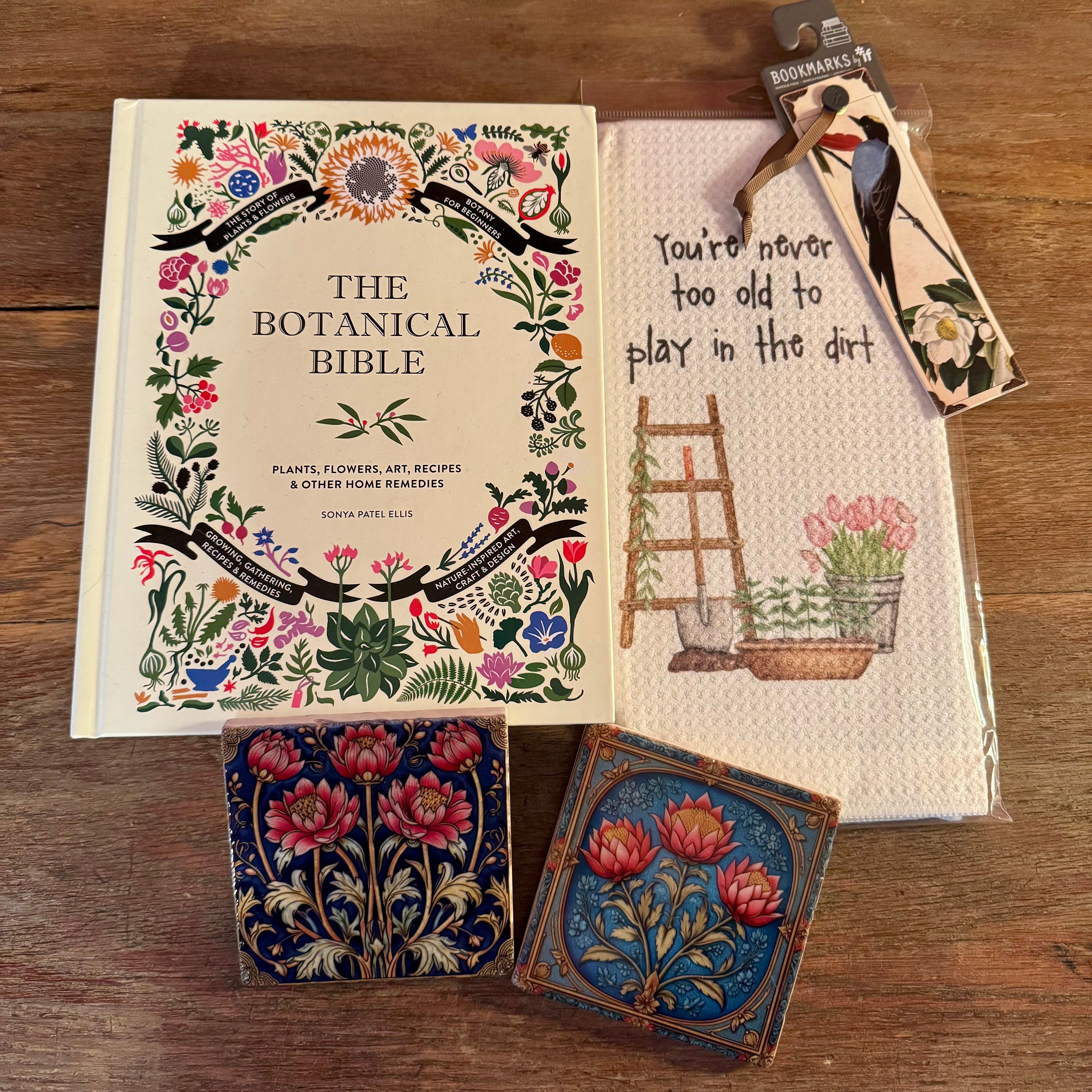 The Botanical Bible book with decorative cards and a towel on a wooden surface